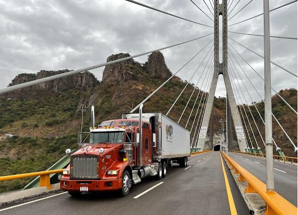 Tractocamion Kenworth de 4D's Trucking con caja refrigerada cruzando un puente atirantado en carretera de montaña